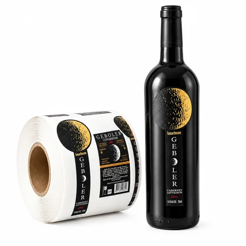 Black wine bottle and matching black-and-gold printed label roll on white